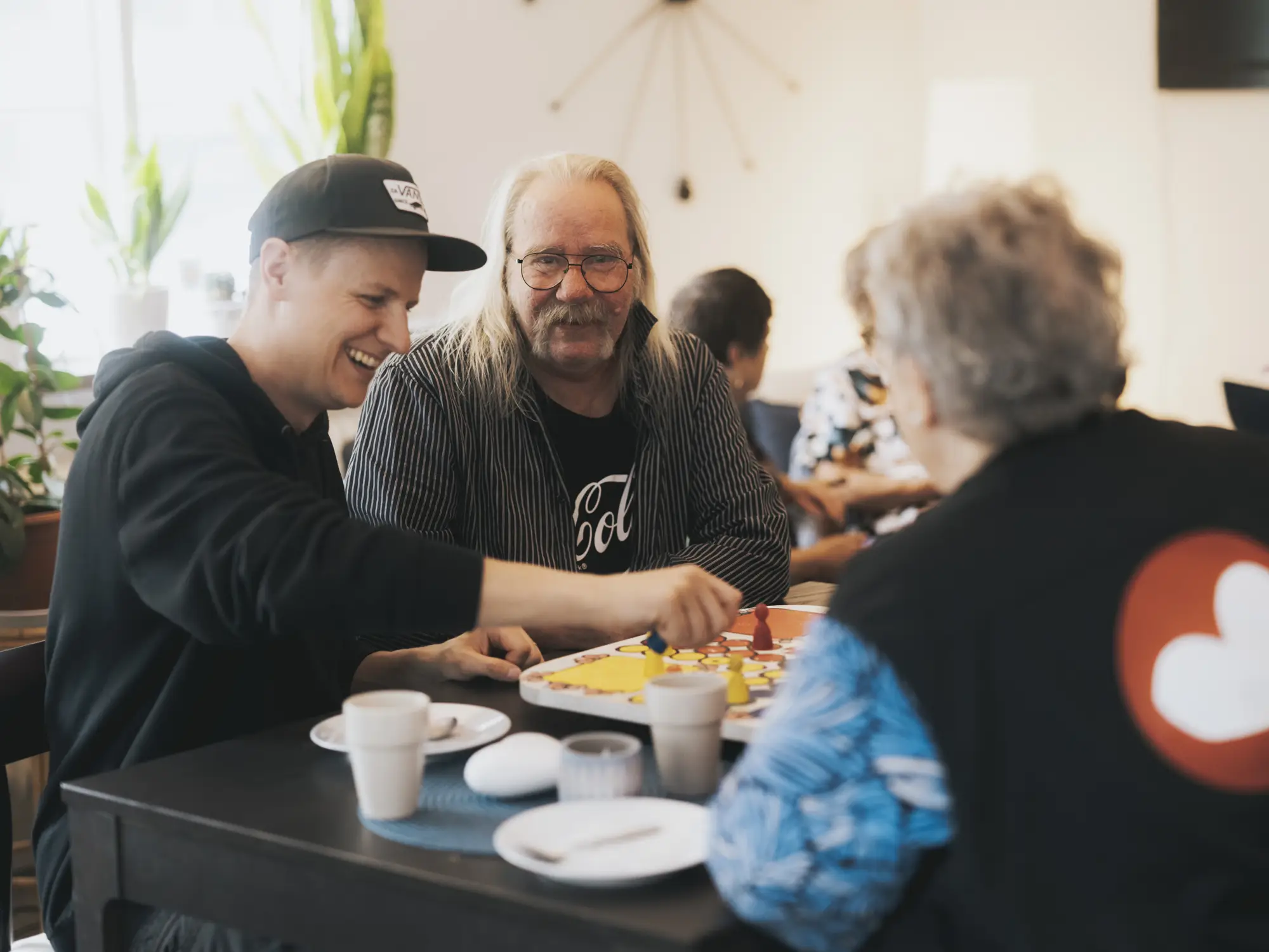 Personer spelar brädspel tillsammans runt ett bord.