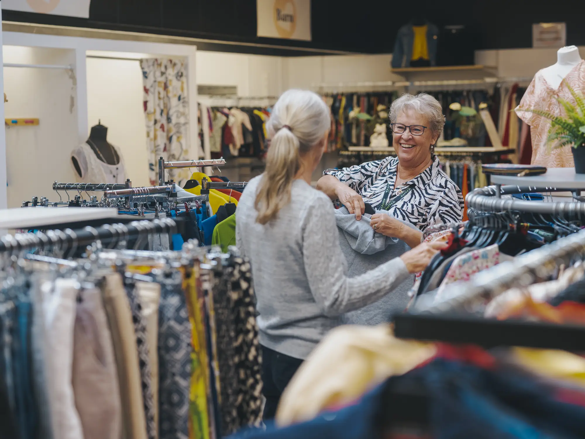 Två personer pratar i en secondhandbutik.